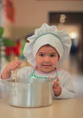 Young child in chef outfit holding a pot – fostering creativity through cooking at Today We Dream