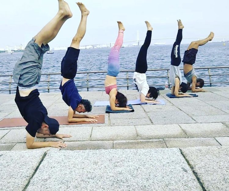 Group practicing yoga headstands by the water – promoting strength and mindfulness through movement
