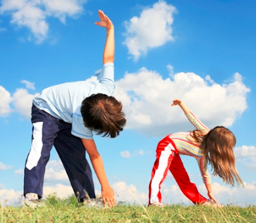 Two children doing side stretches outdoors – promoting active lifestyles and physical wellness
