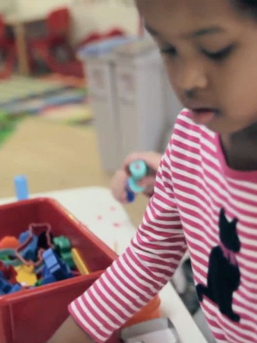 Young child playing with colorful toys at a table in a learning environment