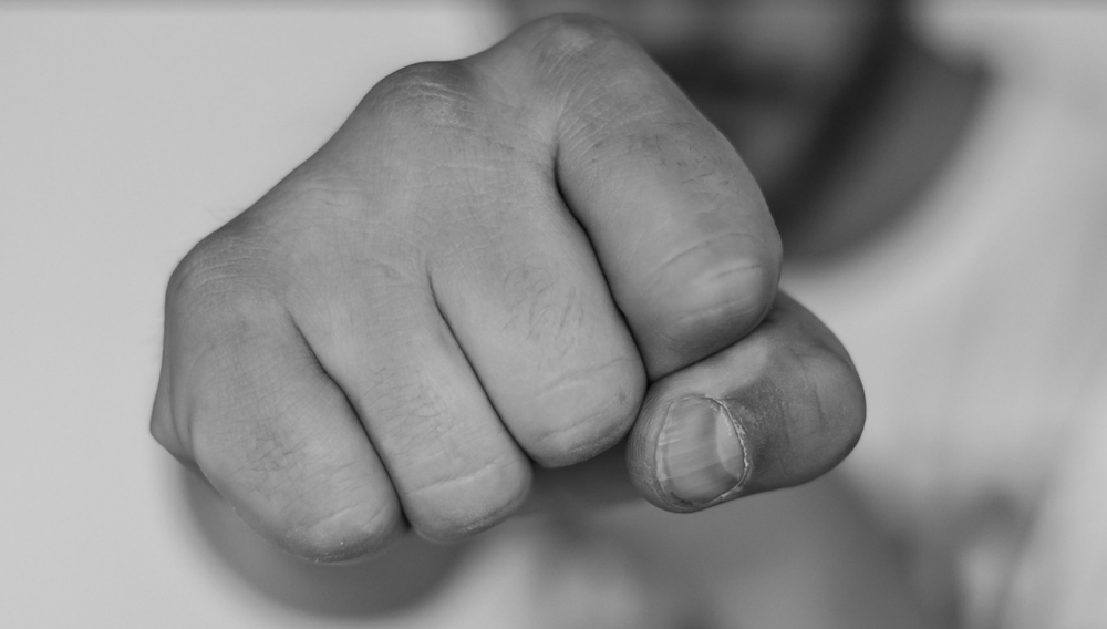 Black-and-white photo of a clenched fist pointed at the camera, evoking a sense of power or conflict
