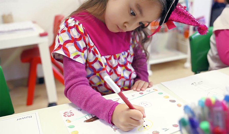 Girl in a party hat focused on drawing – nurturing creativity and concentration through art activities
