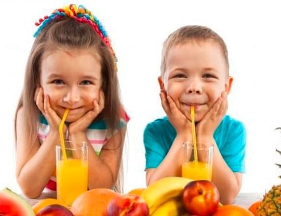 Kids drinking juice with fruits on table – encouraging healthy eating and joyful mealtimes