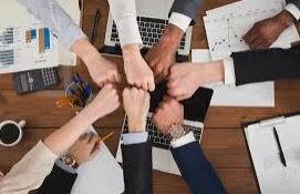 Team of professionals coming together in unity around a table, symbolizing collaboration and collective purpose aligned with Today We Dream’s values.